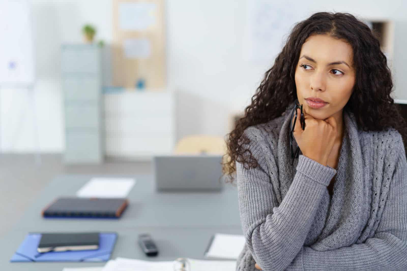 en fundersam tjej med långt svart hår står på kontoret