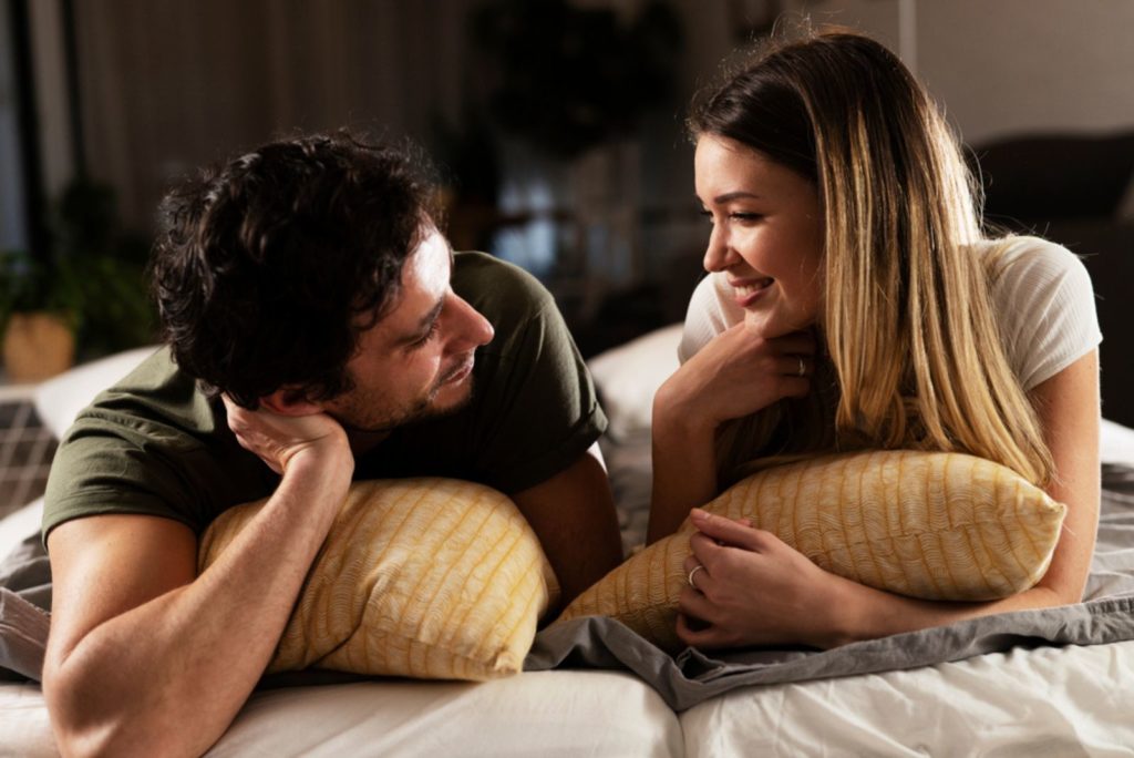 smilende kvinde taler til mand i sengen