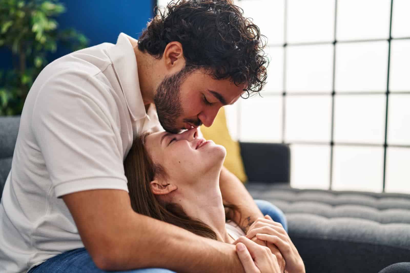 Mand og kvinde kysser næsen og krammer hinanden derhjemme