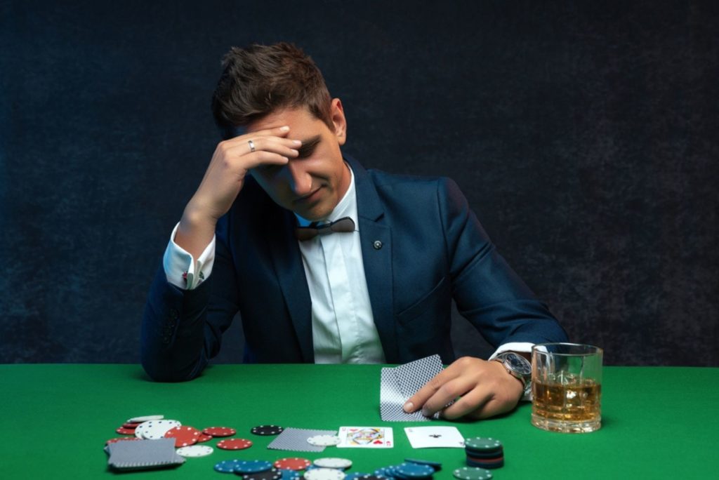Oprørt pokerspiller i kasino med dårlige pokerkort