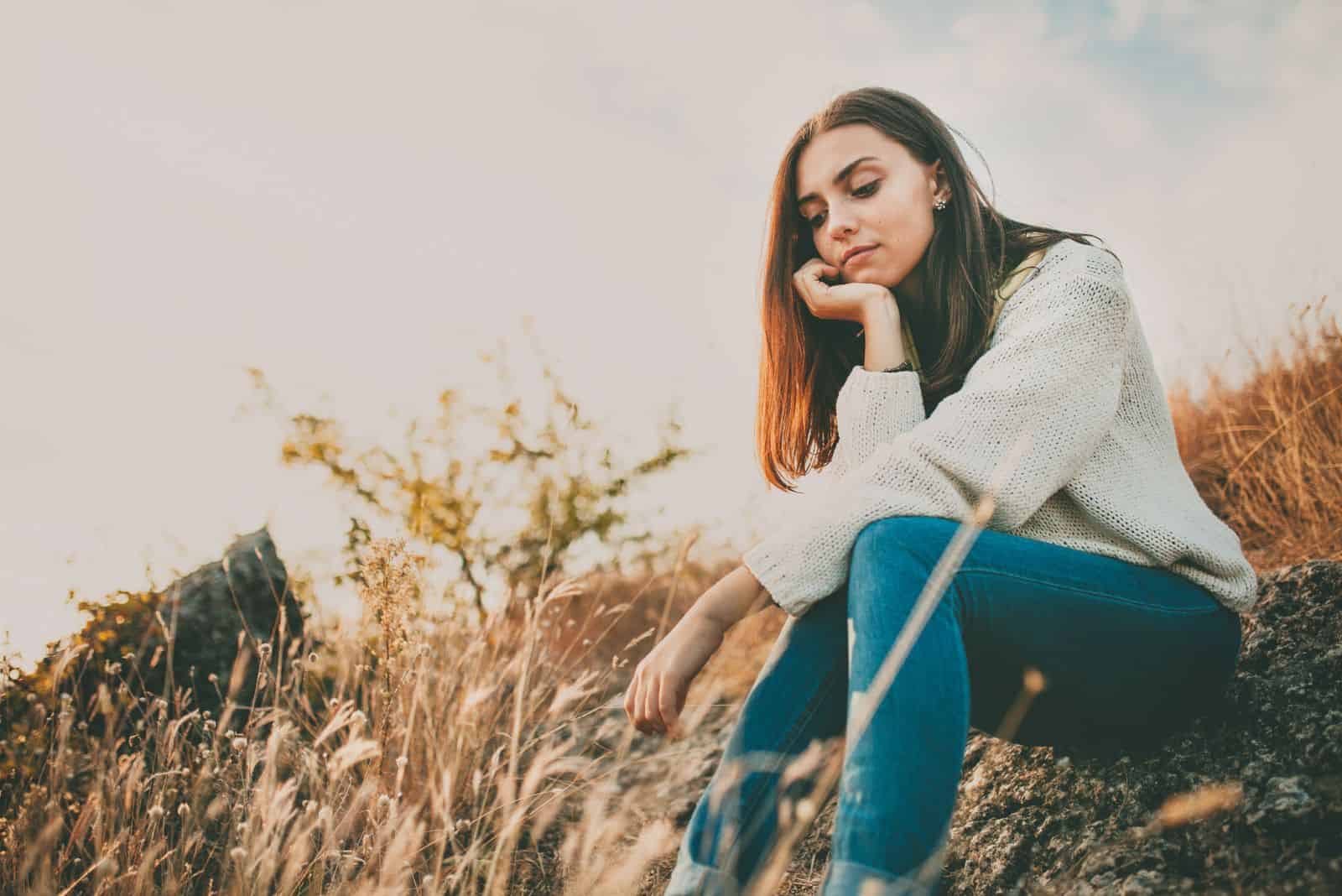 en flicka sitter på ett fält av spannmål