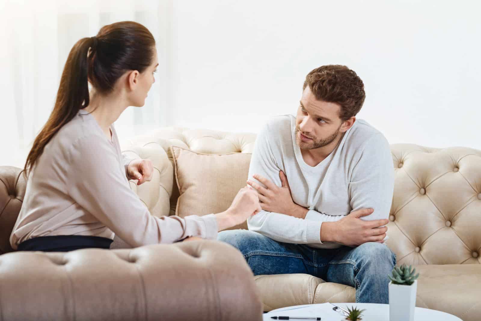 en mann og en kvinne sitter på en sofa og snakker