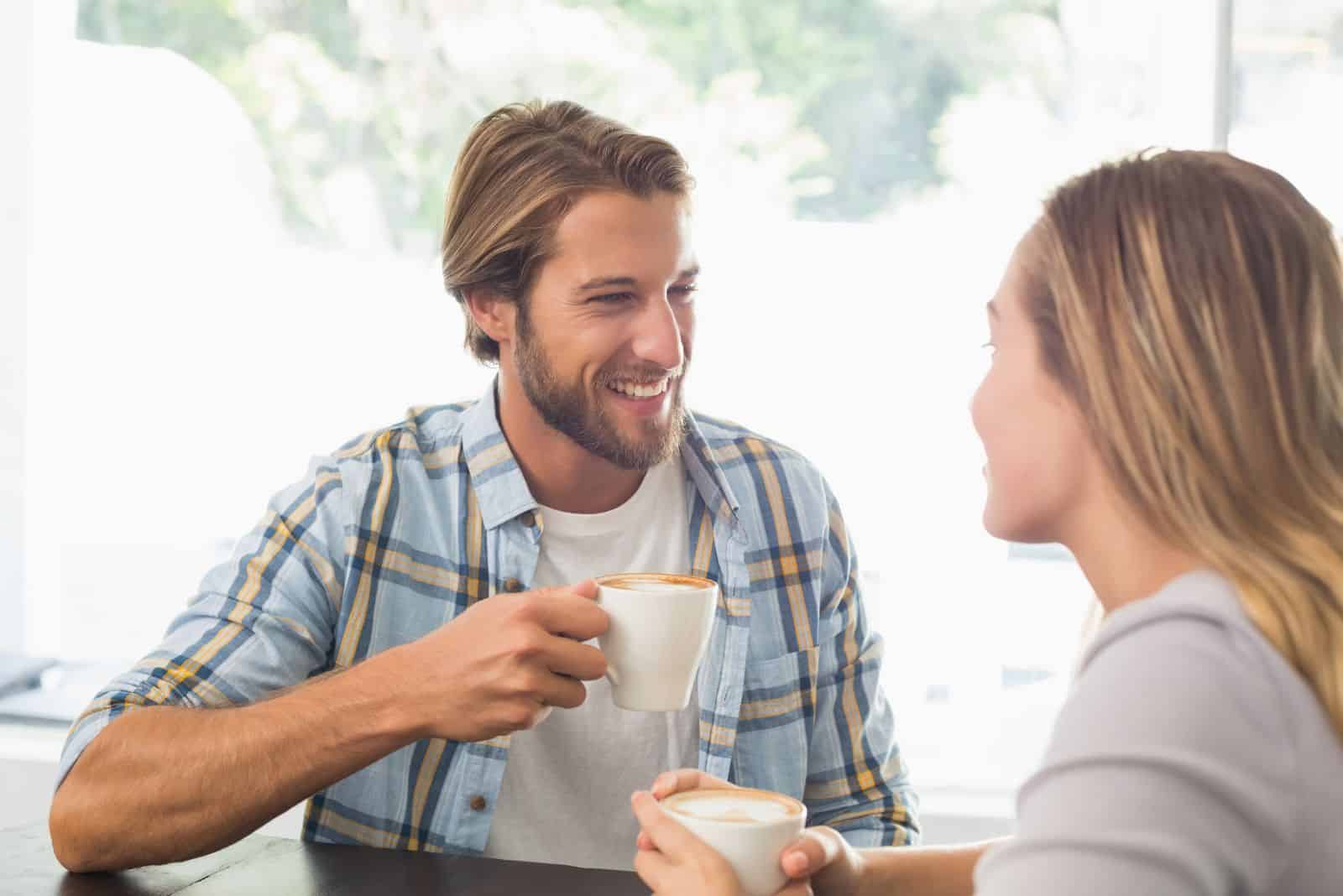 smilende mann snakker med kvinne over kaffe
