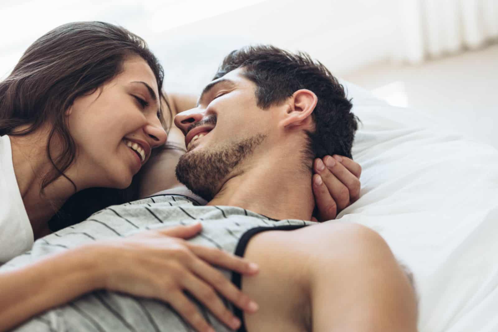 leende man och kvinna gosa i sängen