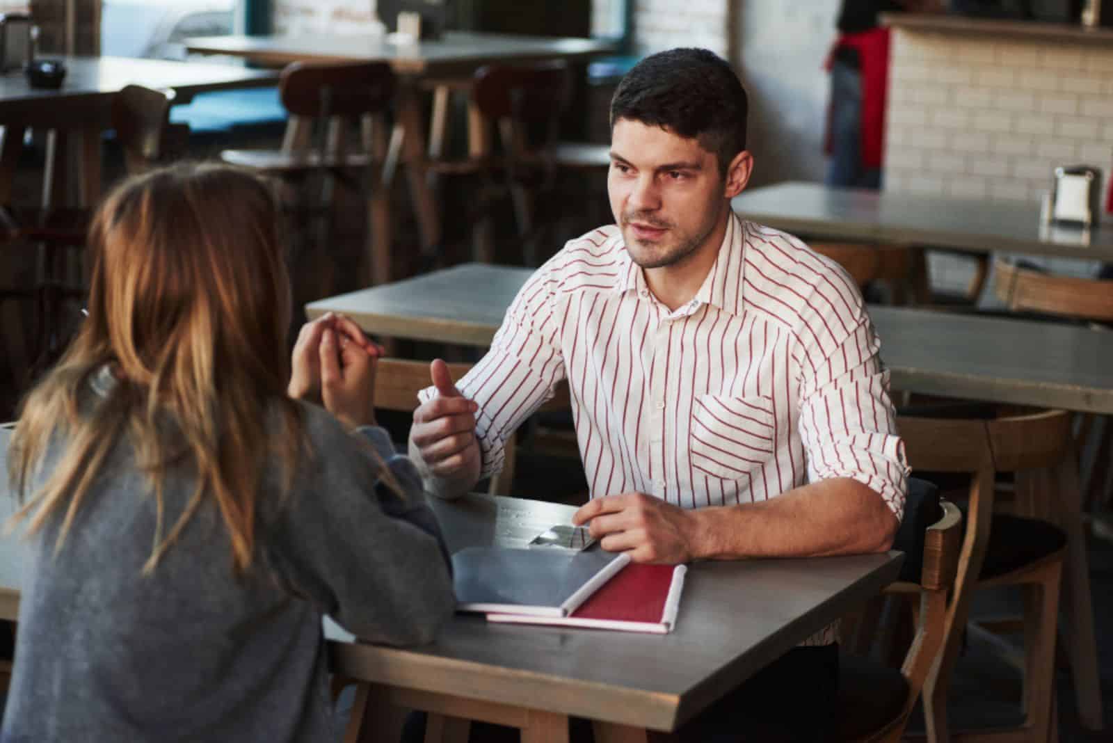 en mann og en kvinne sitter ved et bord på en kafé og snakker