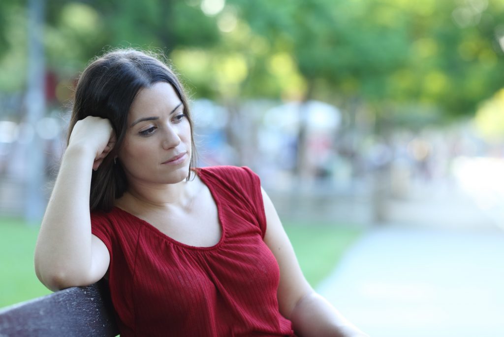 Eftertænksom kvinde sidder på en bænk i en park