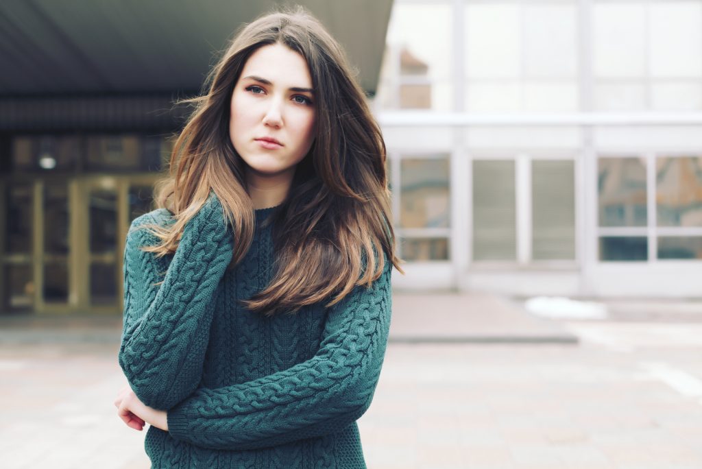 Ung kvinde iført uldgrøn sweater, der går i vintergaden