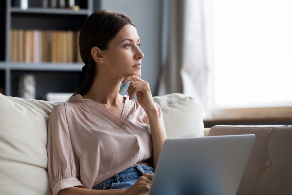 bekymret ung kvinde sidder i sofaen med en bærbar computer