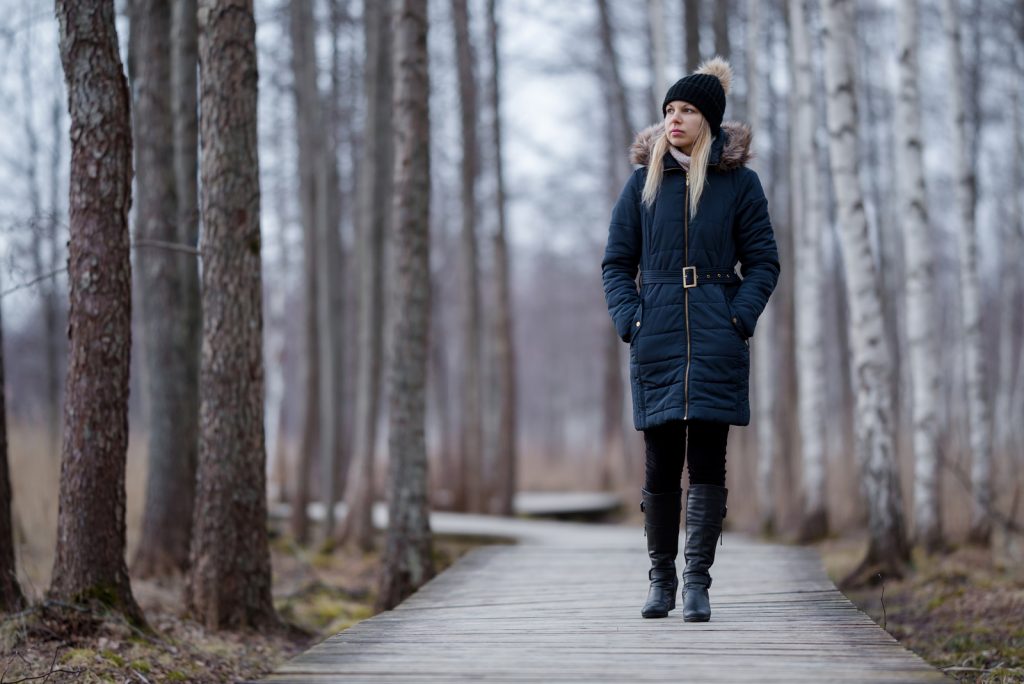 kvinde i mørkt varmt tøj går langsomt på træspor