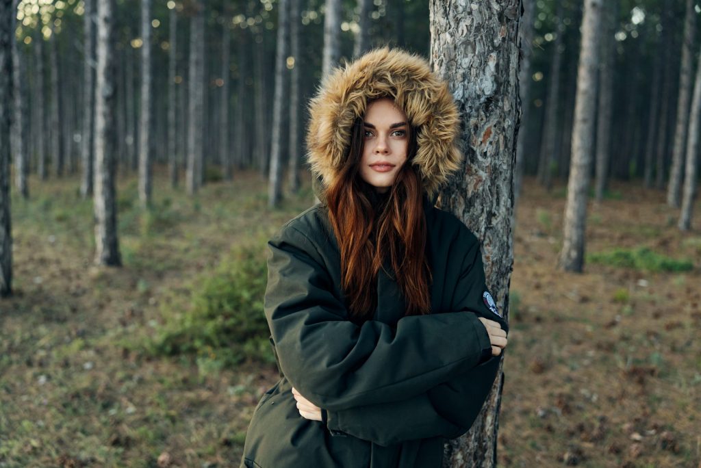 kvinde i varm jakke i skoven