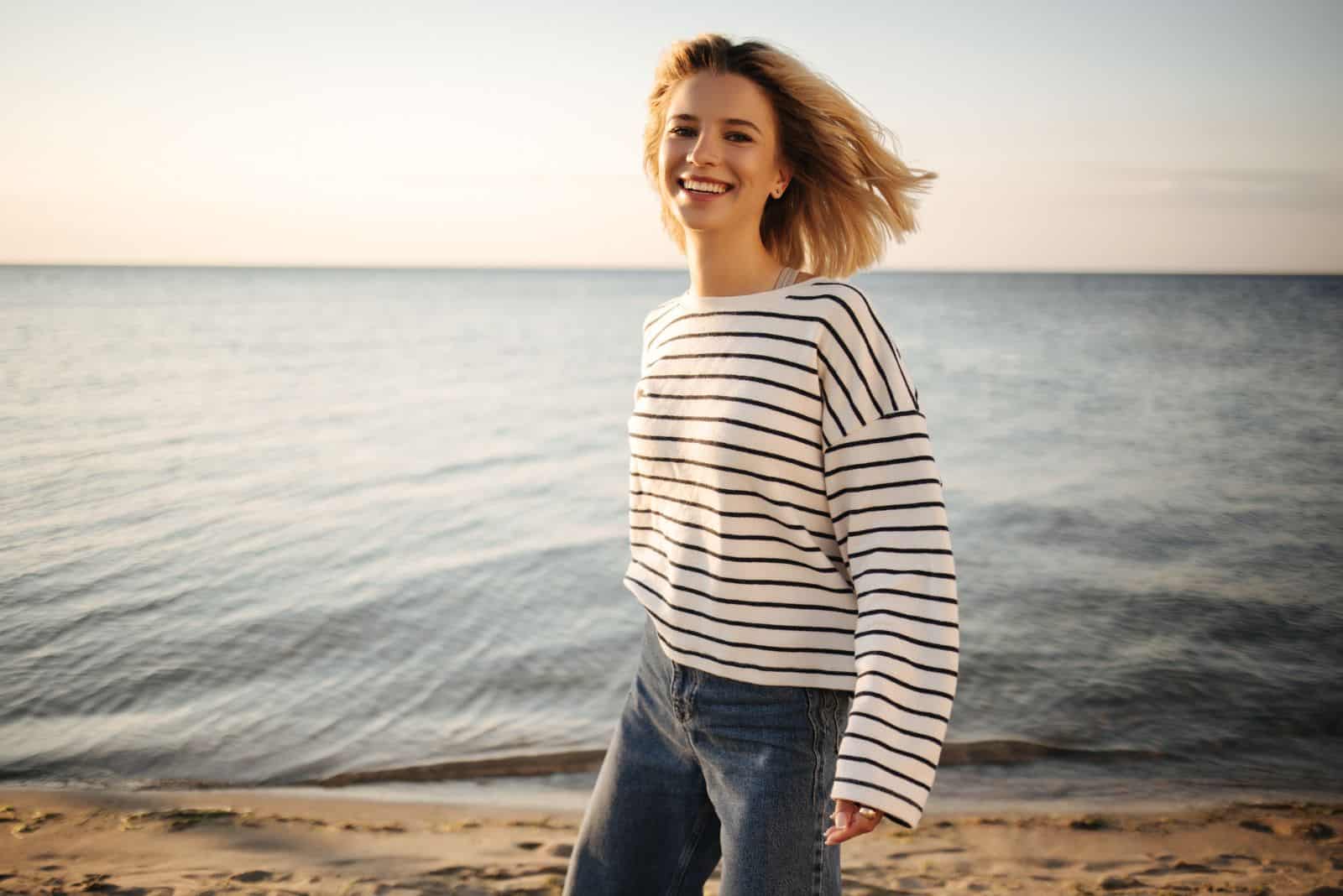 leende flicka står på stranden