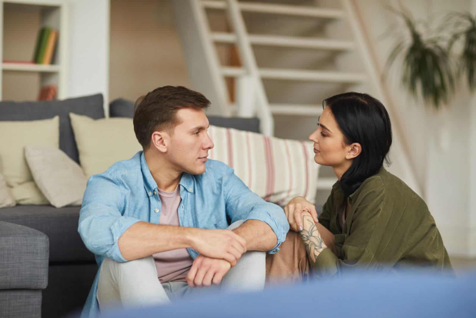 en man och en kvinna sitter på golvet och pratar