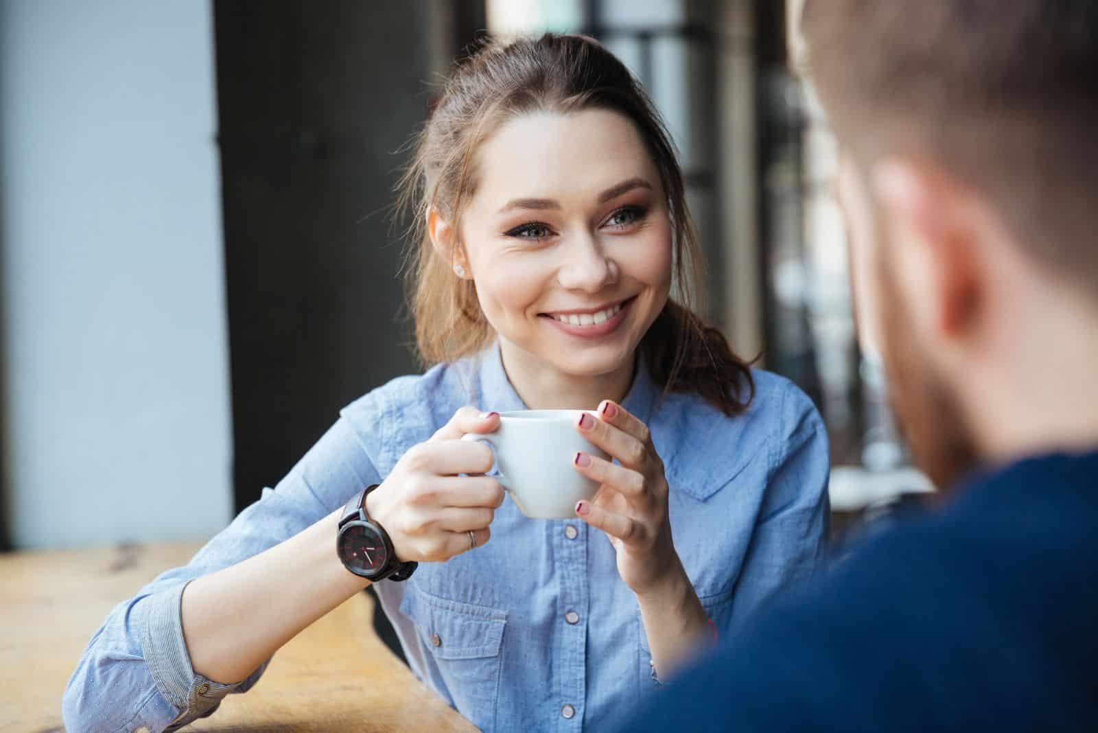 en leende tjej pratar med en man på ett kafé