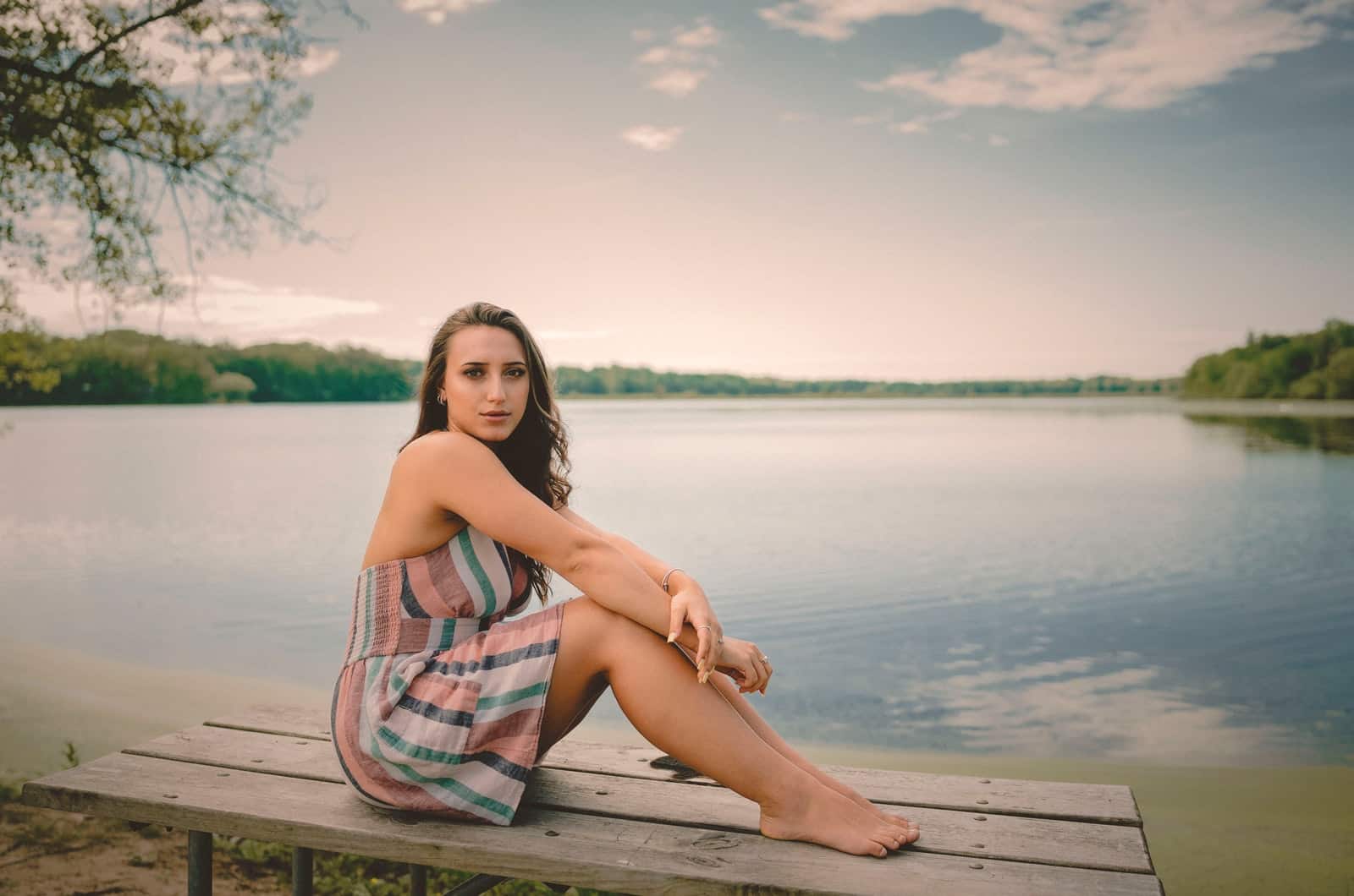 kvinde sidder på en bænk nær en sø