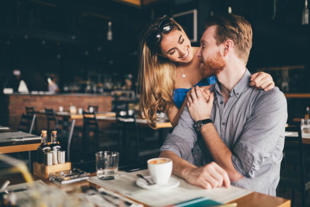 Smuk mand og kvinde flirter i cafe