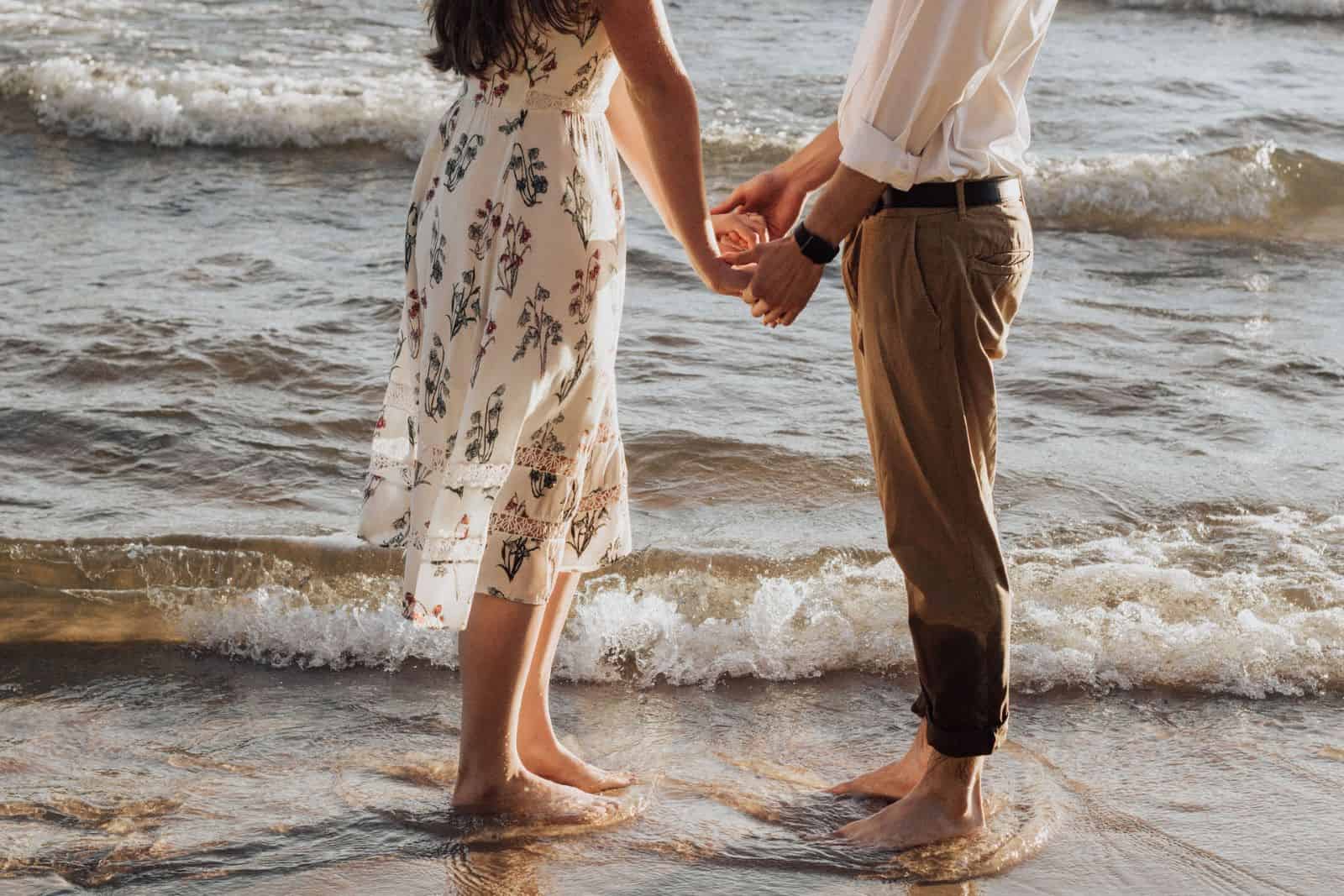 par holder i hånd på stranden