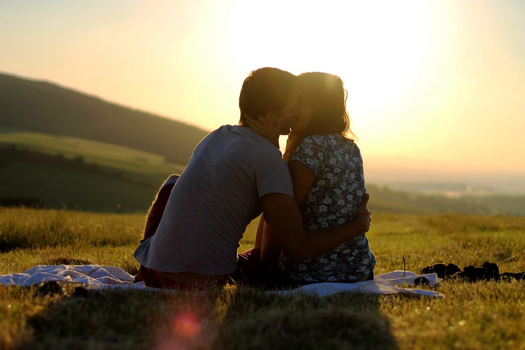 par sidder på græsset kysser